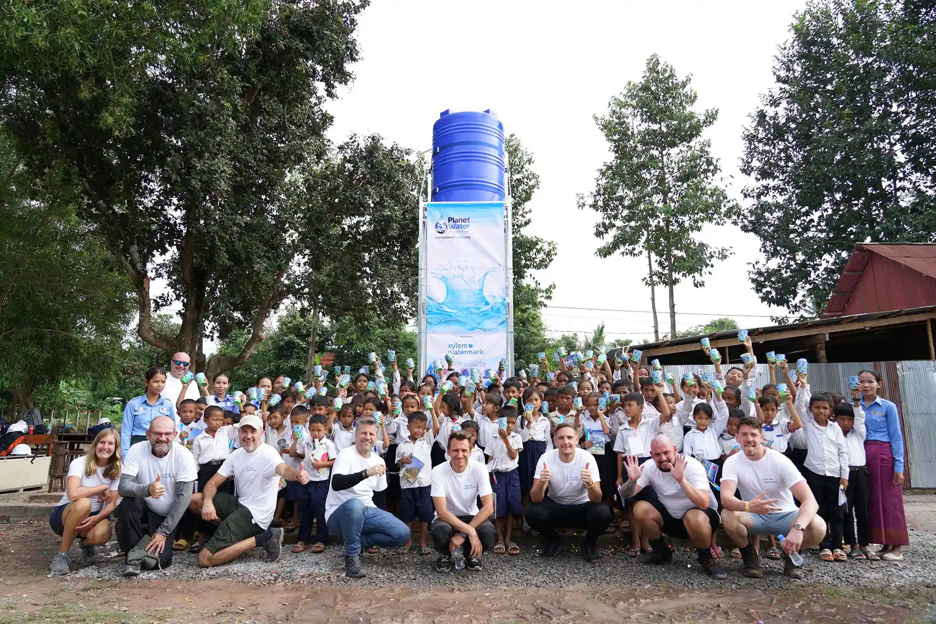 Volunteers, students and teachers posing in front of the water tower